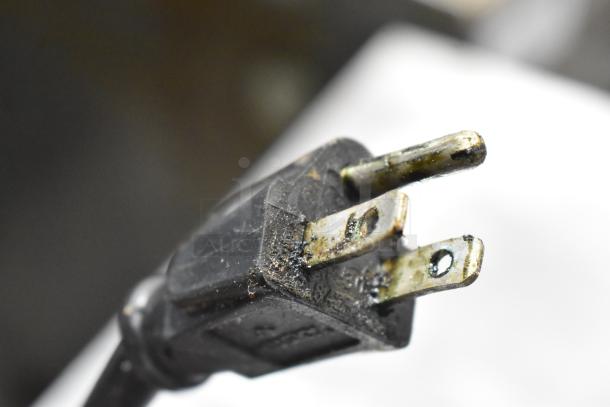 Close-up of a three-pronged power plug attached to an Alto Shaam 750-S heated holding cabinet. Plug shows signs of wear.