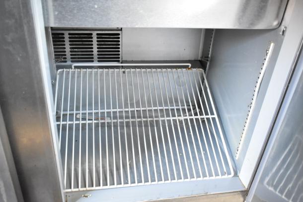 Beverage Air SPE48-18M stainless steel sandwich salad prep table interior with wire shelving, on commercial casters.