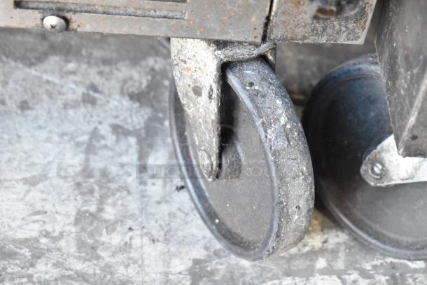 Beverage Air SPE48-18M caster wheel, showing wear and rust, on commercial sandwich salad prep table.