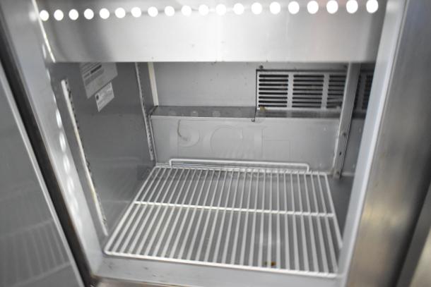 Beverage Air SPE48-18M stainless steel prep table, interior view, features wire shelving and ventilation grates, on casters.