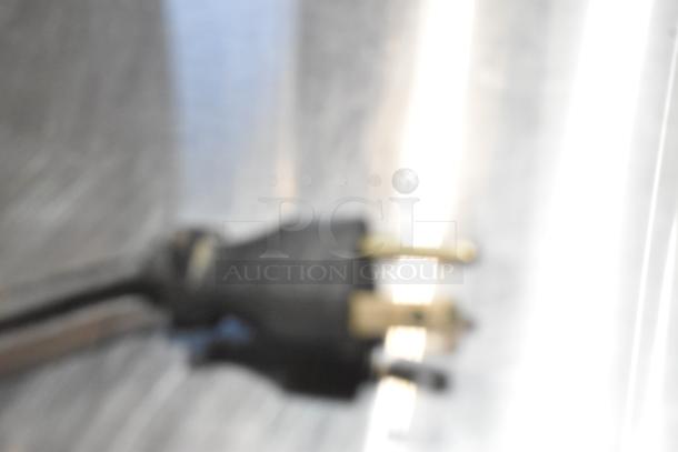 Blurry close-up of a power plug, part of the Bunn ITCB-DV iced tea machine, 120V, stainless steel, for commercial use.