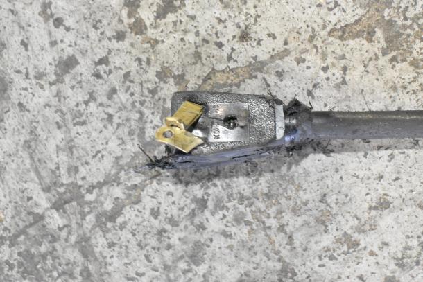 Damaged electrical plug with exposed wires on a concrete floor.