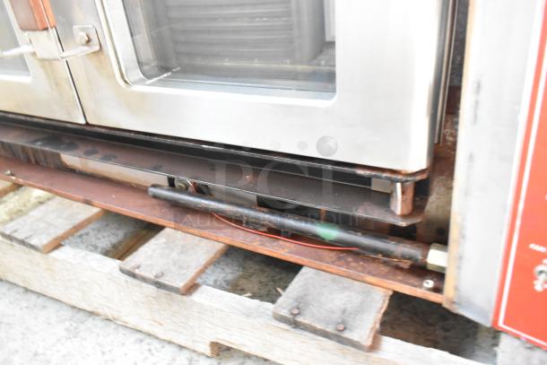 Vulcan VC4GD stainless steel commercial convection oven with view-through doors and metal racks on a pallet. Visible controls.