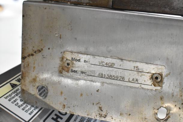 Close-up of a metal tag on a Vulcan VC4GD stainless steel convection oven showing "Mod. no: VC4GD" and "Ser. no: 481385926".