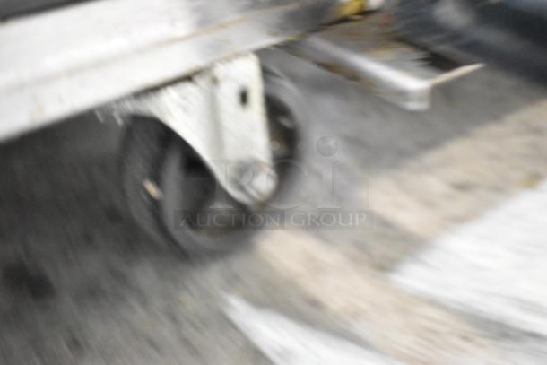 Blurry close-up of a caster on a Turbo Air MST-48-18 stainless steel sandwich salad prep table.