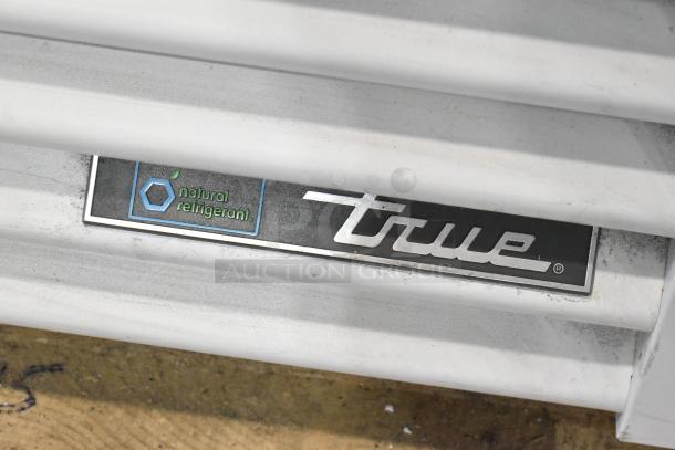 True TSCI-600R-G-PH cooler tag, "natural refrigerant" label shown. Metal slats partially visible.