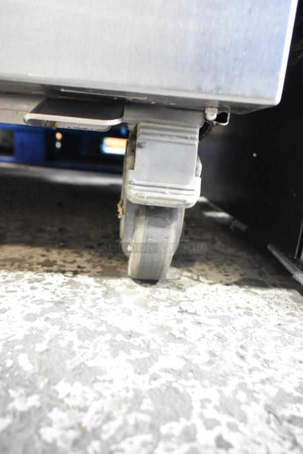 JBT 2ND-GEN-MFJ-HE citrus juicer's caster on textured floor, showcasing mobility feature for commercial use.