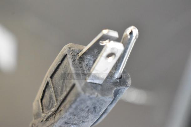 Close-up of a power plug for a Frigidaire EFRF698-6COM freezer, showing prongs and part of the casing with visible markings.