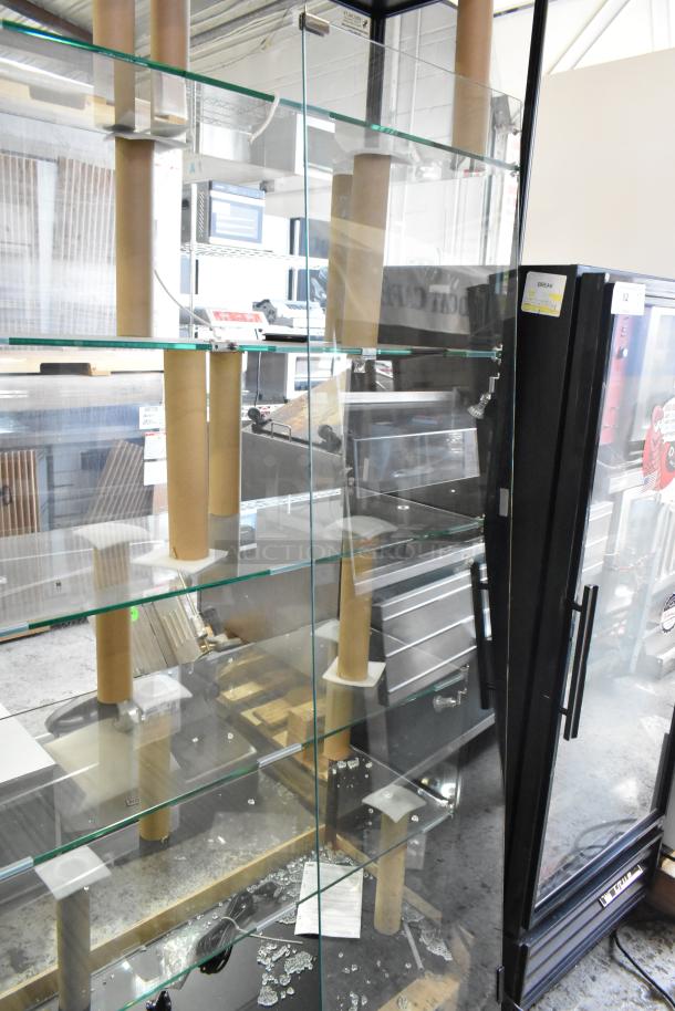 Metal and glass dry display case with broken glass panels. Multiple glass shelves supported by cardboard tubes.