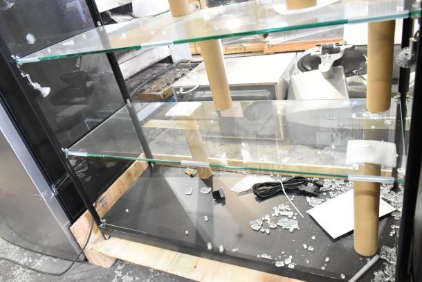 Metal and glass dry display case with broken glass shelves, scattered glass pieces, and a visible electrical cord.