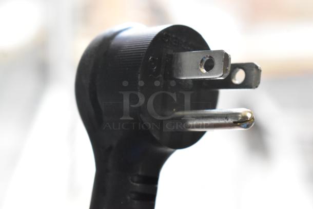 Close-up of a three-prong electrical plug for the 2021 True TSCI-600R-G-PH reach-in cooler, showing metal prongs and plastic casing.