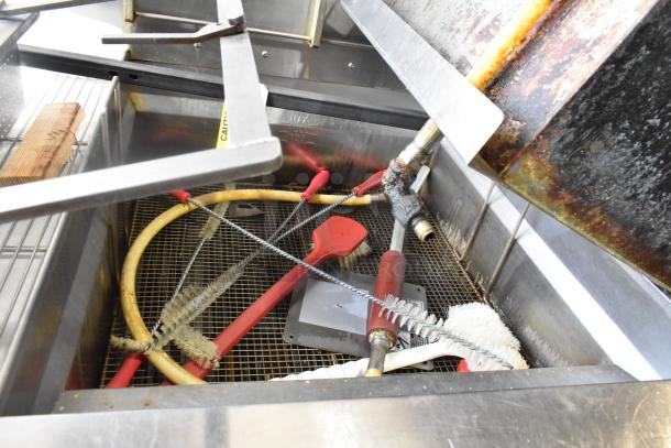 Giles EOF-24 stainless steel 3-bay deep fat fryer with center dumping station, showing cleaning tools inside, on commercial casters.