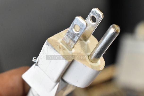 Close-up of a worn, white electrical plug with metal prongs showing signs of use.