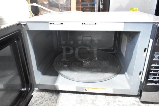 Panasonic NN-SN975S countertop microwave oven with metal finish, open door showing interior and glass plate. 120 volts, 1 phase.