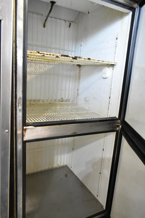True T-23F-2 stainless steel freezer, two half-size doors, commercial casters, 115 volts, 1 phase, visible wear inside.