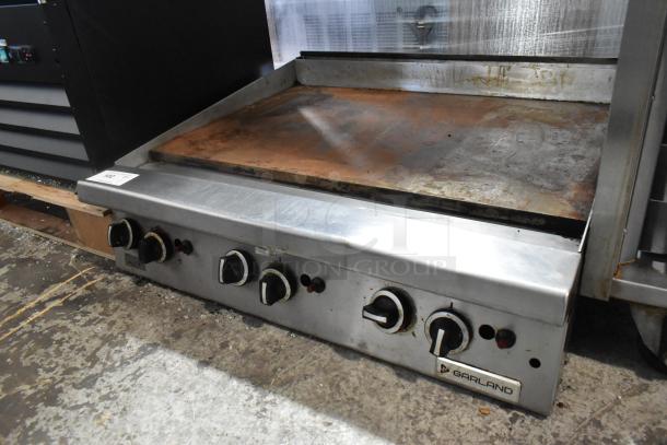 Garland stainless steel commercial gas griddle, featuring a flat top design. Multiple control knobs visible, used condition.