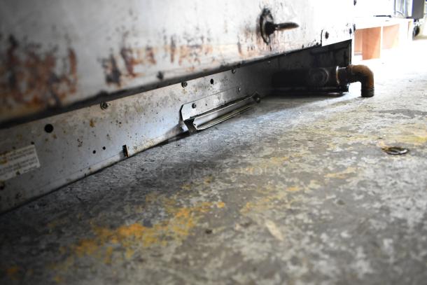 Garland Stainless Steel Commercial Gas Griddle, shows rust and wear, visible pipe connection, industrial kitchen equipment.
