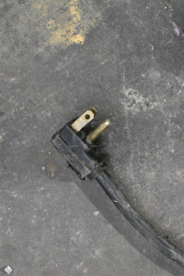 Power cord plug of a Globe Metal Chest Freezer. 115 Volts, 1 Phase. Black, three-prong design with moderate wear.