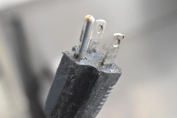 Close-up of a three-prong plug for the Hoshizaki F-330BAJ commercial ice machine, showing wear and surface marks.