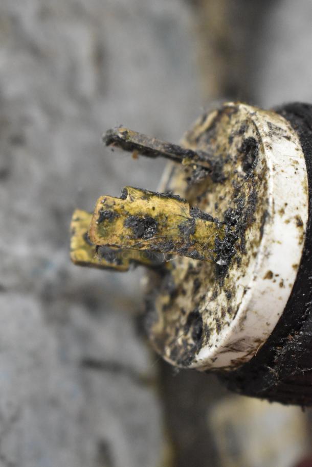 Rusty electrical plug with visible dirt and corrosion on metal prongs, close-up view.