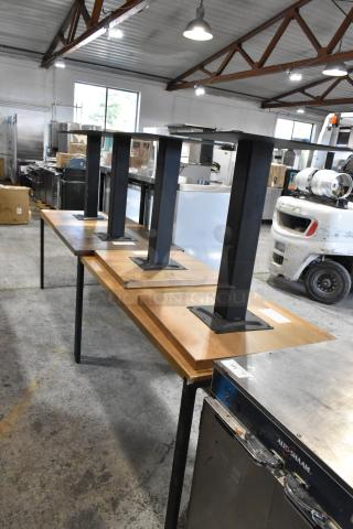 6 wooden tables with metal legs in warehouse, slightly used condition, varied wood tones, ideal for industrial decor.