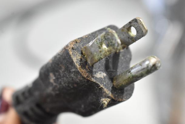 Close-up of a weathered electrical plug, part of a 120-volt, 1-phase appliance, showing signs of wear and corrosion.
