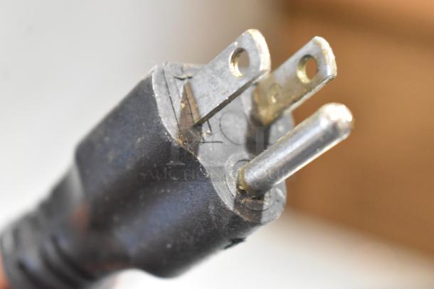 Close-up of a standard 3-prong electrical plug with slight dirt, compatible with 120 volts, 1 phase appliances.