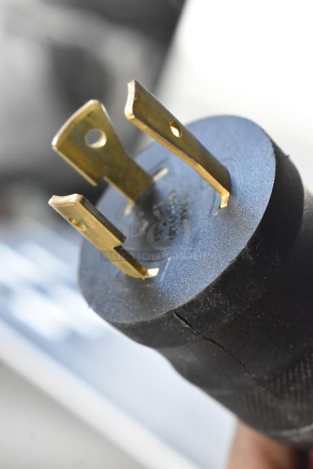 Close-up of a power plug for the Grindmaster 1000662GM Ecoboiler, showing metal prongs and slight wear on the plastic casing.