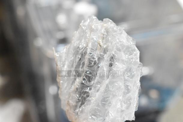 Bubble-wrapped item, likely the Avantco 177BW48 hot dog bun warmer, brand new with scratch and dent. Stainless steel.