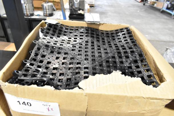 2 boxes of brand new Choice 176BM12BK 12" x 12" black interlocking bar mats, scratch and dent condition, auction label visible.