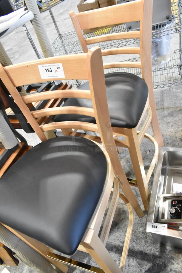 Bar height chairs, brand new, scratch and dent condition. Wooden frames, black cushioned seats. Auction tag 193 visible.
