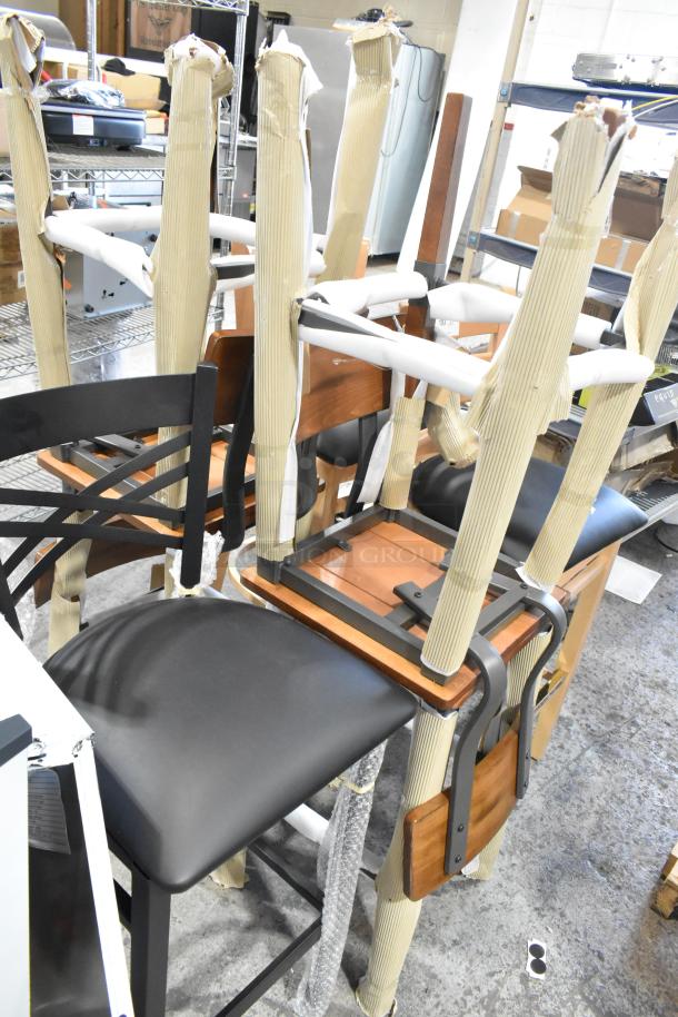 Seven brand new scratch and dent bar height chairs with black seats and wood accents, protective wrapping visible.