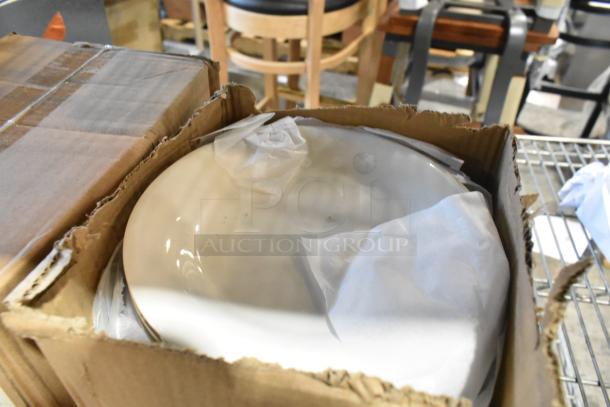 Four new boxes of assorted white ceramic dishes in partially opened packaging; some items labeled "scratch and dent."