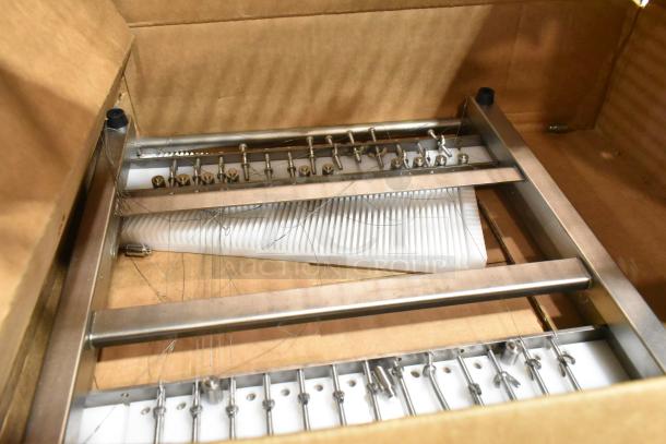 Brand new metal unit with visible scratches and dents, featuring metal brackets and hardware, in an opened cardboard box.