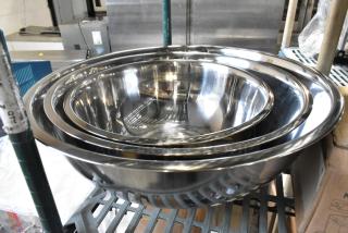 Three new metal bowls with slight scratches and dents, stacked on a shelf. Shiny stainless steel construction, durable design.