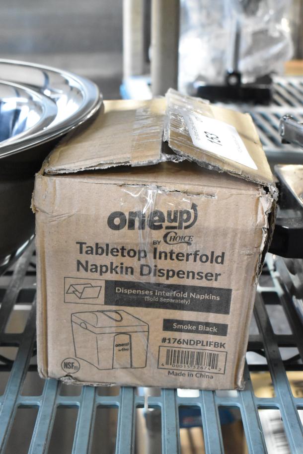 Brand new Choice Smoke Black tabletop interfold napkin dispenser in original box, model #176NDPLIFBK. Box slightly dented.