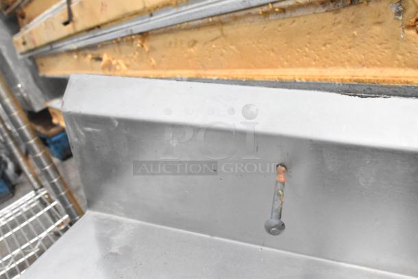 Stainless steel counter with sink bay, faucet, and handles. No legs. Used condition, some wear visible.
