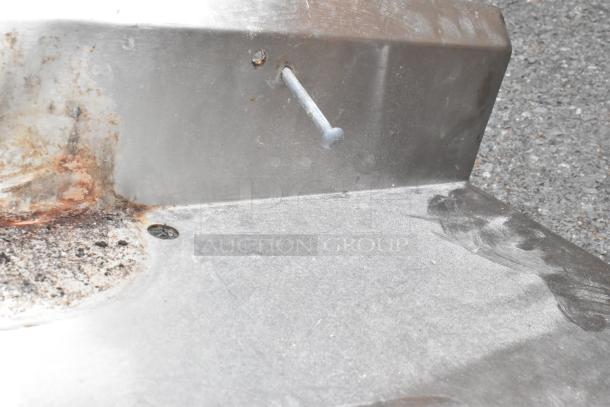 Stainless steel counter with sink bay and faucet. Features handles. Shows rust and wear. Missing legs.