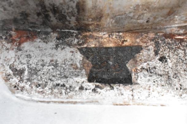 Rusted, weathered surface detail of a stainless steel counter with sink bay. No legs or additional features visible.
