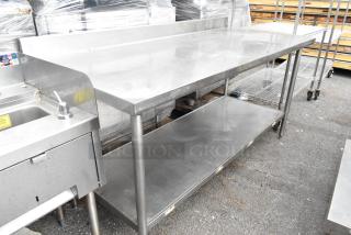 Stainless steel table with backsplash and under shelf, used condition, durable design, ideal for commercial kitchens.