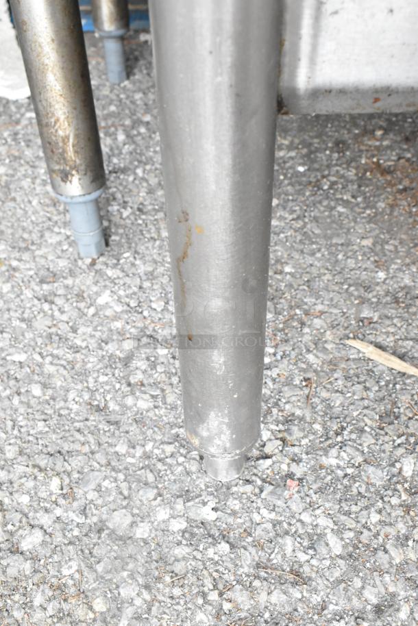 Stainless steel table leg with visible wear and rust. Durable construction, under shelf support, suitable for heavy-duty use.