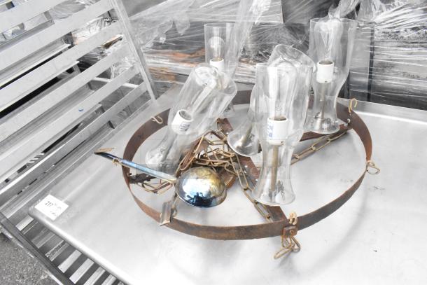 Stainless steel table with under shelf and pan rack, features various glass fixture contents and chains, in used condition.