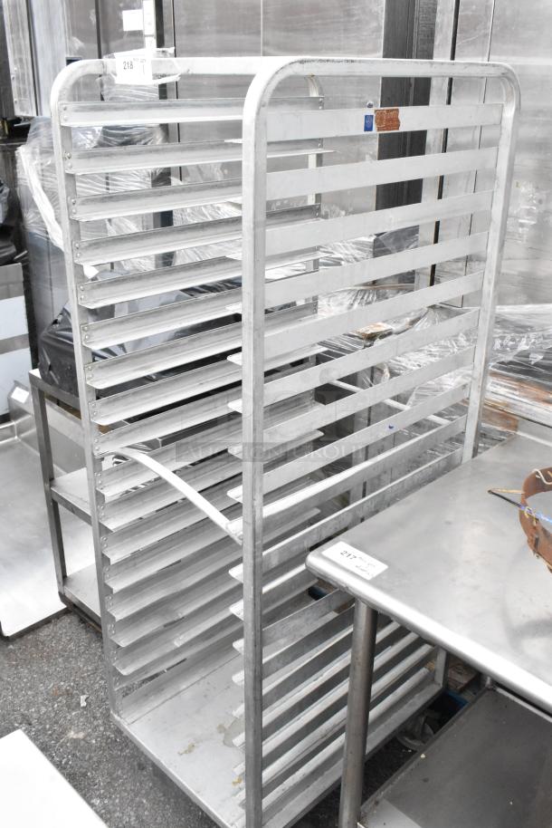 Metal pan transport rack with multiple shelves, mounted on commercial casters. Appears in used condition. Suitable for kitchens.