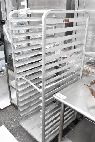 Metal pan transport rack with multiple shelves, mounted on commercial casters. Appears in used condition. Suitable for kitchens.