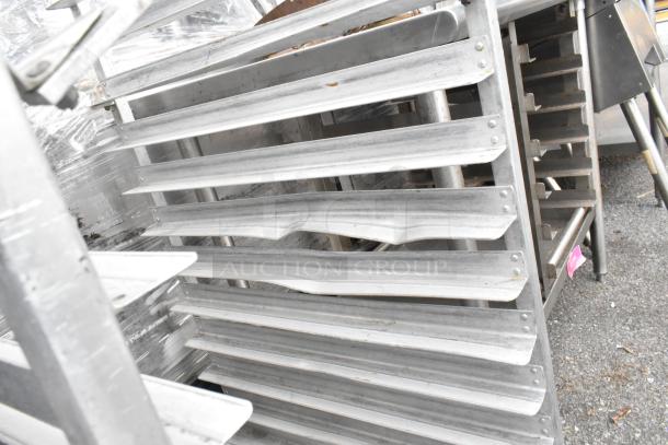 Metal pan transport rack with multiple shelves on commercial casters, showing a sturdy metal frame and slight wear.