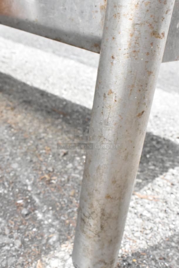 Close-up of a stainless steel table leg showing signs of wear and rust, part of a table with under shelf and two-tier over shelf.