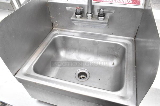 Stainless steel single bay wall mount sink with faucet and handles, shown with visible wear and minor rust spots.