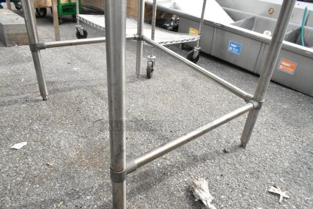 John Boos stainless steel table, sturdy frame, visible surface wear, suitable for commercial kitchen use, on casters.