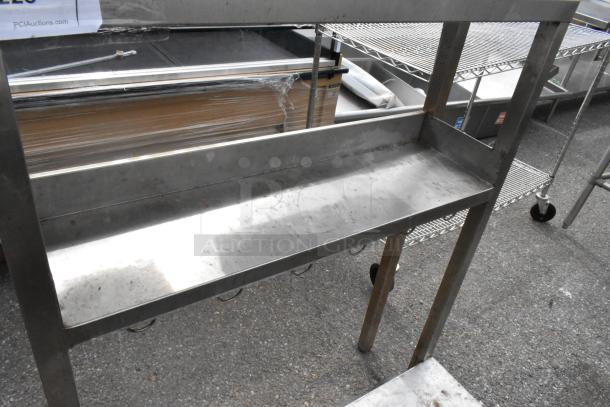 Metal table with under shelf, stainless steel, used condition, sturdy frame, ideal for kitchen or workshop use.
