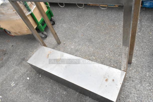 Metal table with an under shelf. Features a sturdy design with visible rust and wear, ideal for industrial use.